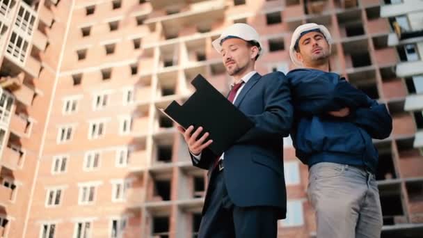 Hombres de negocios en cascos en la construcción de edificios — Vídeos de Stock