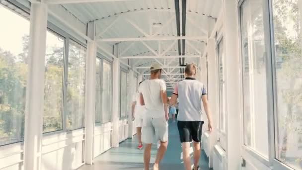 Люди ходят по коридору с окнами — стоковое видео