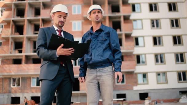 Hombres de negocios en cascos en la construcción de edificios — Vídeos de Stock