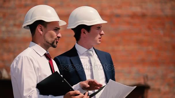 Бізнесмени в шоломах на будівництві будівель — стокове відео