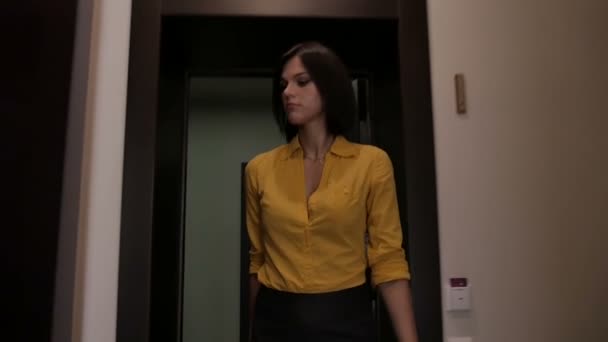 スーツケースで黄色のシャツのブルネットの女性実業家がホテルの部屋に入る — ストック動画