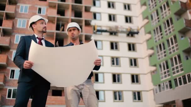 Hombres de negocios en cascos en la construcción de edificios — Vídeos de Stock