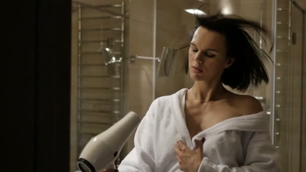 自宅の浴室で乾燥した髪を白いローブでブルネットの女性 — ストック動画