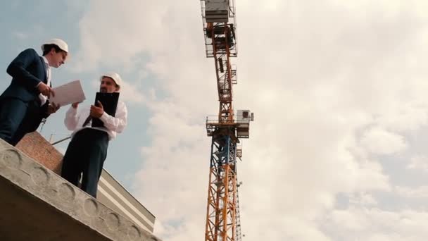 Hombres de negocios en cascos en la construcción de edificios — Vídeo de stock