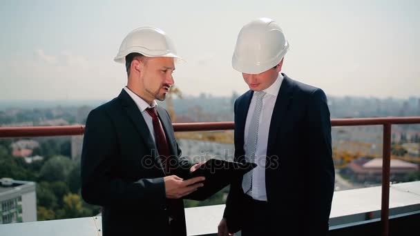 Hombres de negocios en cascos en la construcción de edificios — Vídeo de stock