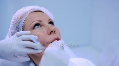 sarışın orta yaşlı kadın kozmetik kliniğinde yüz içine enjeksiyon yapıyor doktor