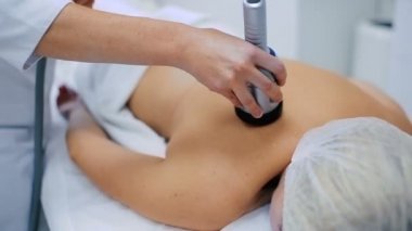 kozmetik kliniğinde modern aparatı ile vücut cilt gençleştirme yapıyor doktor