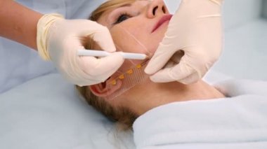 sarışın orta yaşlı kadın kozmetik kliniğinde çehresini içine kalem kullanarak doktor