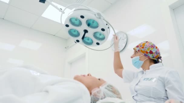 美容クリニックの中の高齢女性の顔に注射を行う医師 — ストック動画