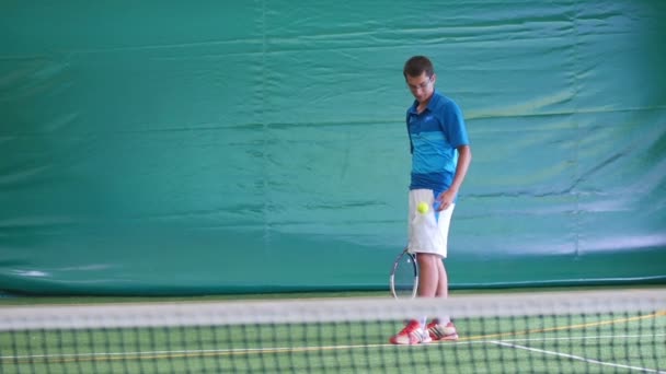 Молодой человек играет в большой теннис — стоковое видео