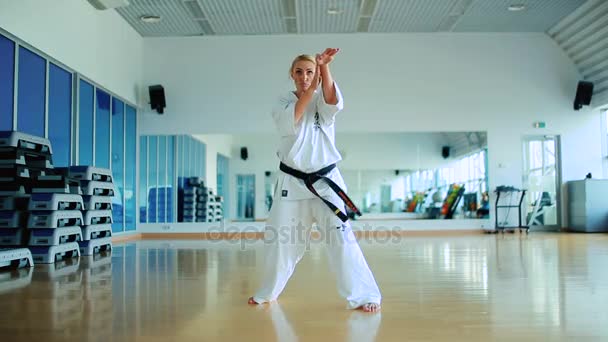 Blonde vrouw beoefenen van karate in sportschool — Stockvideo