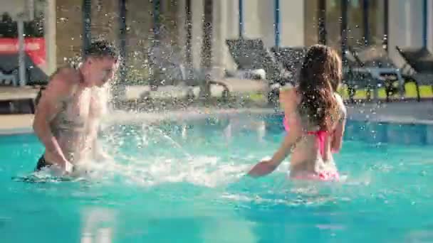 Vrouw spelen met man in buitenzwembad — Stockvideo