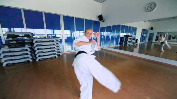 Mujer joven practicando karate en el gimnasio — Vídeo de stock