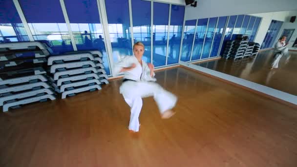 Jonge vrouw beoefenen van karate in sportschool — Stockvideo