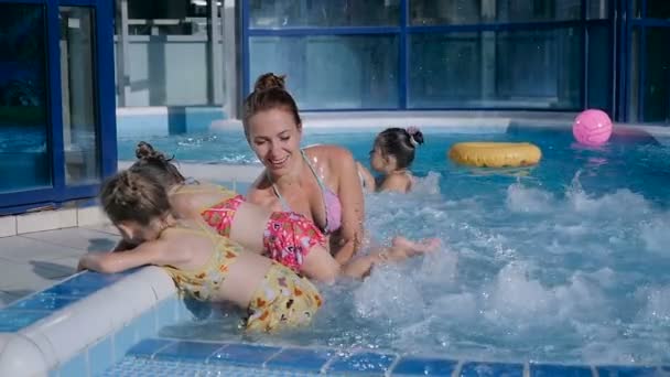 Женщина брызгает с девушками в бассейне — стоковое видео