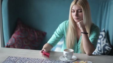 Telefonunuzun ve kafede kahve fincanı ile mavi gömlekli sarışın genç kadın