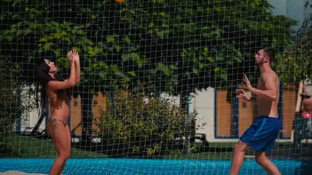 Vrouw met jonge man spelen volleybal — Stockvideo