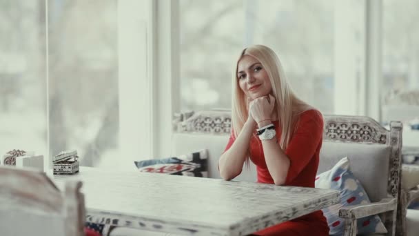 カフェで赤いドレスの若いブロンドの女性 — ストック動画