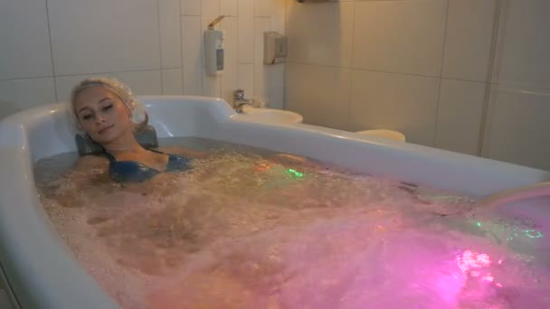 Женщина в шапочке для душа, лежащая в ванной — стоковое видео