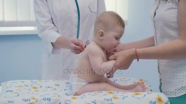 Küçük çocuk bebek bezi üzerinde oturur.