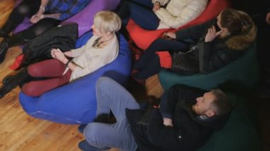 Genç insanlar komik performans ve gülümseme izliyor. Adam ve yastıklar katta oturan kadın.