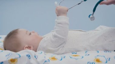 Şirin bebek bebek bezi üzerinde bırakır. Doktor çok güzel çocuk üzerinde eğilir. O küçük çocuk stetoskop verdi. Şirin bebek dikkatlice onun elinde tıbbi ekipman görünüyor. Doktor eller dokunur çocuk.