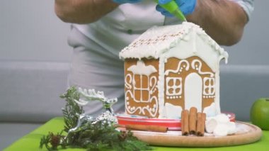 Yakın çekim. Kamera yavaş yavaş soldan sağa doğru hareket ediyor. Pudra evi beyaz krema ile süsle. Erkek krem krem enjektör evin çatısına iter.