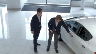 iki genç iş adamları yakınındaki büyük camları olan modern showroom, beyaz araba siyah takım elbise 