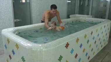 Genç Baba erkek çocuk havuzunda su altında yüzmek bebek öğretim. Bebek denizden ortaya çıkıyor..