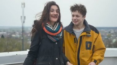 Çatıda duran iki mutlu çocuk. Güzel esmer tepeden sanal gerçeklik gözlükleri çıkar. Gülümseyen kız ve adam için fotoğraf makinesini ve baş parmak işareti gösterir. İnsanlar Çatıda iyi eğlenceler.