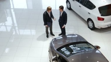 siyah takım elbiseli iki genç işadamları iki büyük camları olan modern showroom arabalara yakın: 