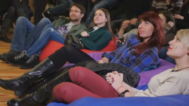 Jóvenes Viendo Actuación Cómica Sonrisa Hombres Mujeres Sentados Suelo Sobre — Vídeos de Stock