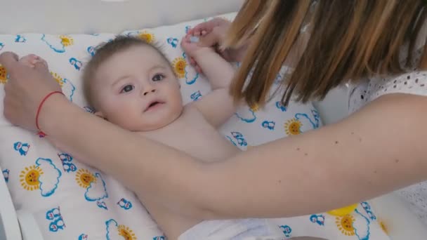 Close Uma Criança Deita Fralda Mãe Segure Bebê Pelas Mãos — Vídeo de Stock