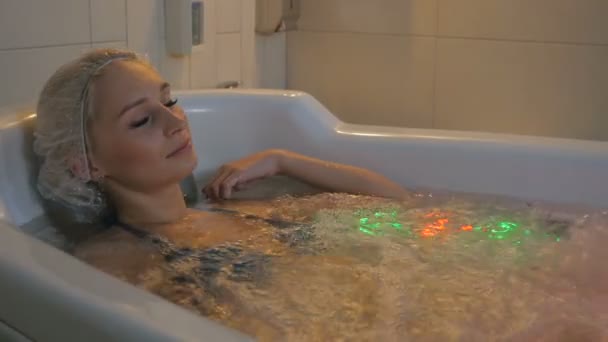 Frau mit Duschhaube liegt in Badewanne — Stockvideo