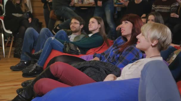 Jóvenes Viendo Actuación Cómica Sonrisa Hombres Mujeres Sentados Suelo Sobre — Vídeos de Stock