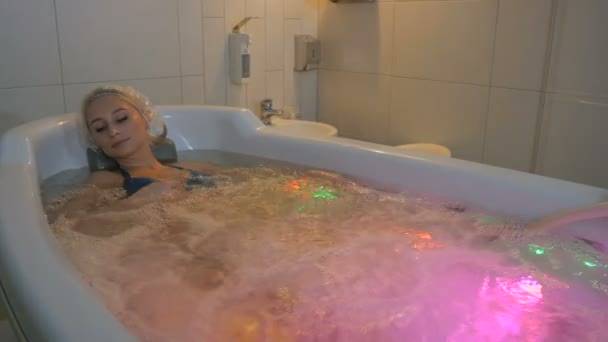 Frau mit Duschhaube liegt in Badewanne — Stockvideo