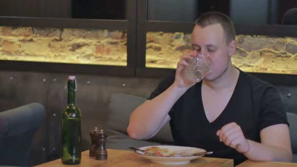 Mann trinkt Wasser und isst Essen — Stockvideo