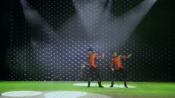 Двое красивых мужчин в плащах и цилиндрах танцуют на сцене — стоковое видео