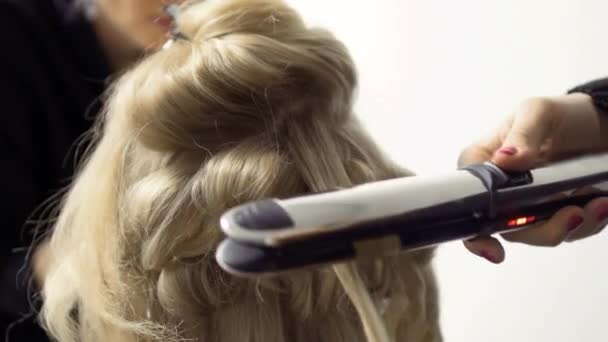 Парикмахер делает прическу с утюгом для женщины — стоковое видео