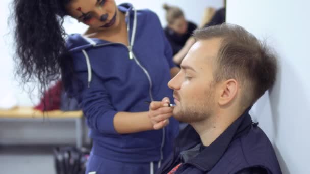 Žena s hroznou líčidlo na tvář pomoci kolega a make-up pro mu — Stock video