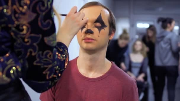 Visagist maakt greasepaint aan een jonge man in theater — Stockvideo