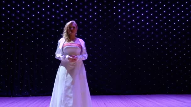 Красивая женщина в белом длинном платье поет чувственную песню на сцене — стоковое видео