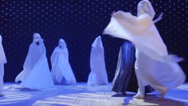 Vacker kvinna i lång klänning dansar med främlingar i kappor på scenen — Stockvideo