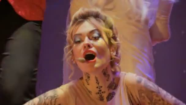 밝은 의상에서 아름 다운 여자는 무대에서 마이크에 노래를 노래 — 비디오