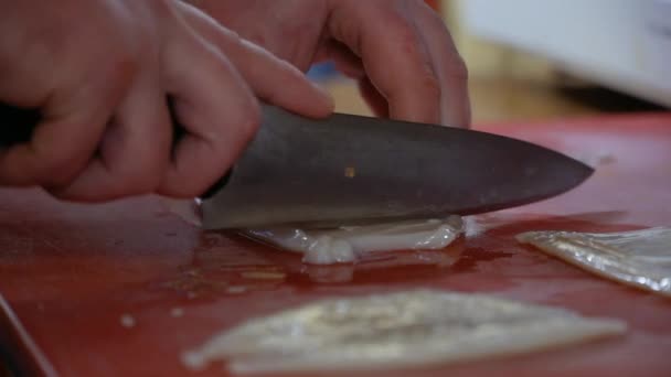 Шеф-повар режет кальмаров на доске в ресторане на кухне — стоковое видео