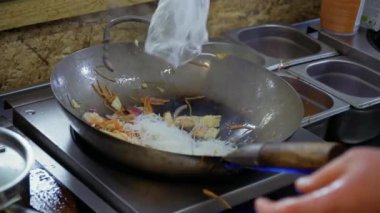 Kızarmış sebze ile sıcak bir tava içine pirinç noodle koymak aşçı