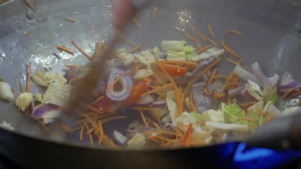 Шеф-повар смешивает овощи в горячей сковороде — стоковое видео