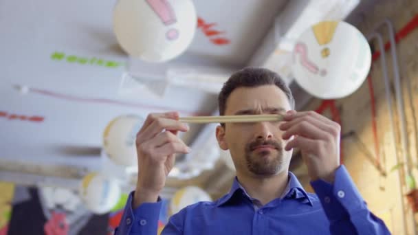 Unga rolig kille stänger näsa med kinesiska ätpinnar på grund av dålig lukt — Stockvideo