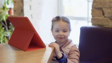 Sevimli küçük kız dijital tablet kafede kullanır.