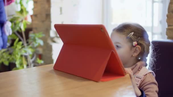 Carino bambina utilizza tablet digitale nel caffè — Video Stock